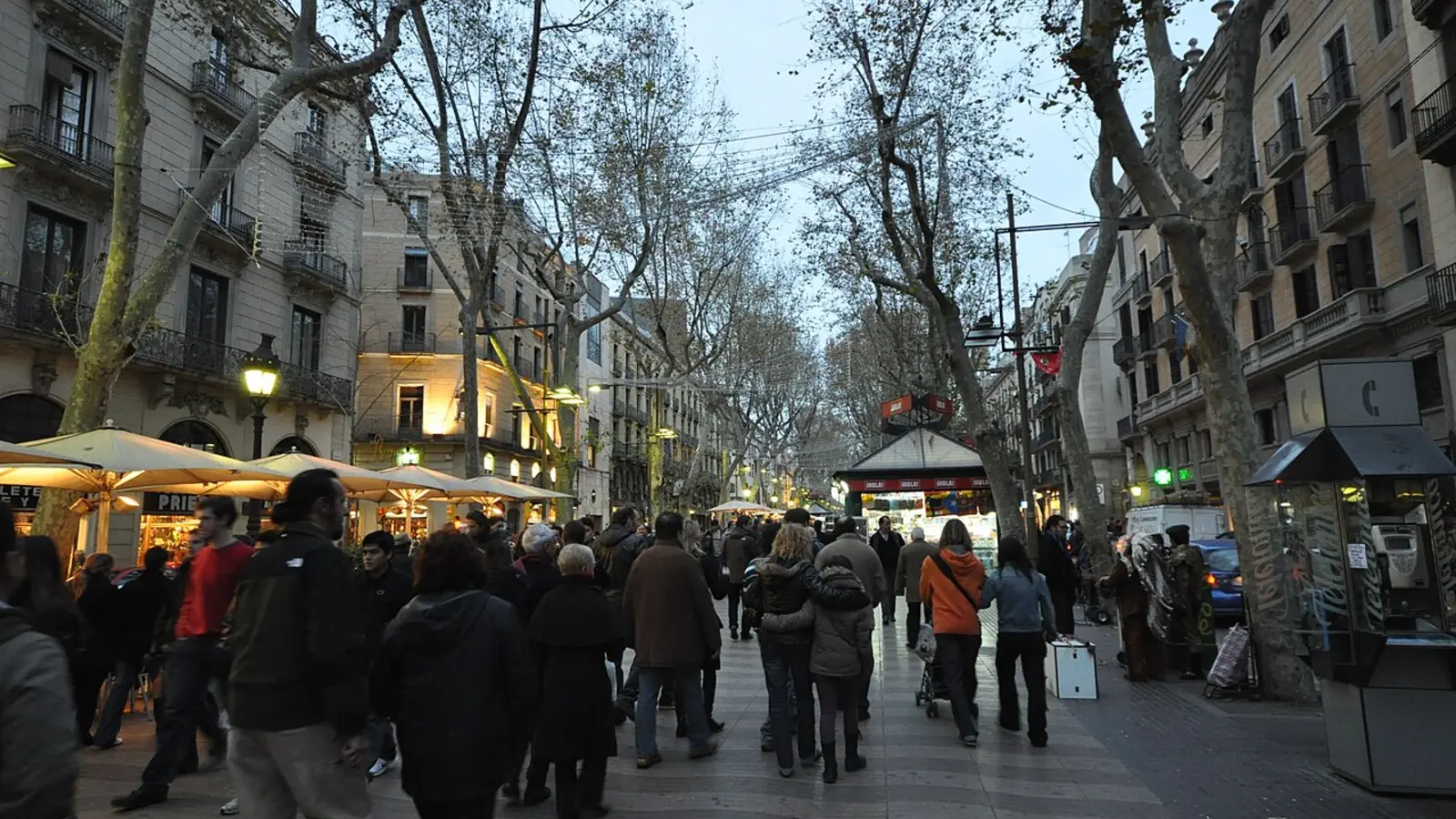 Crowded tourist promenade on La Rambla in Barcelona at dusk